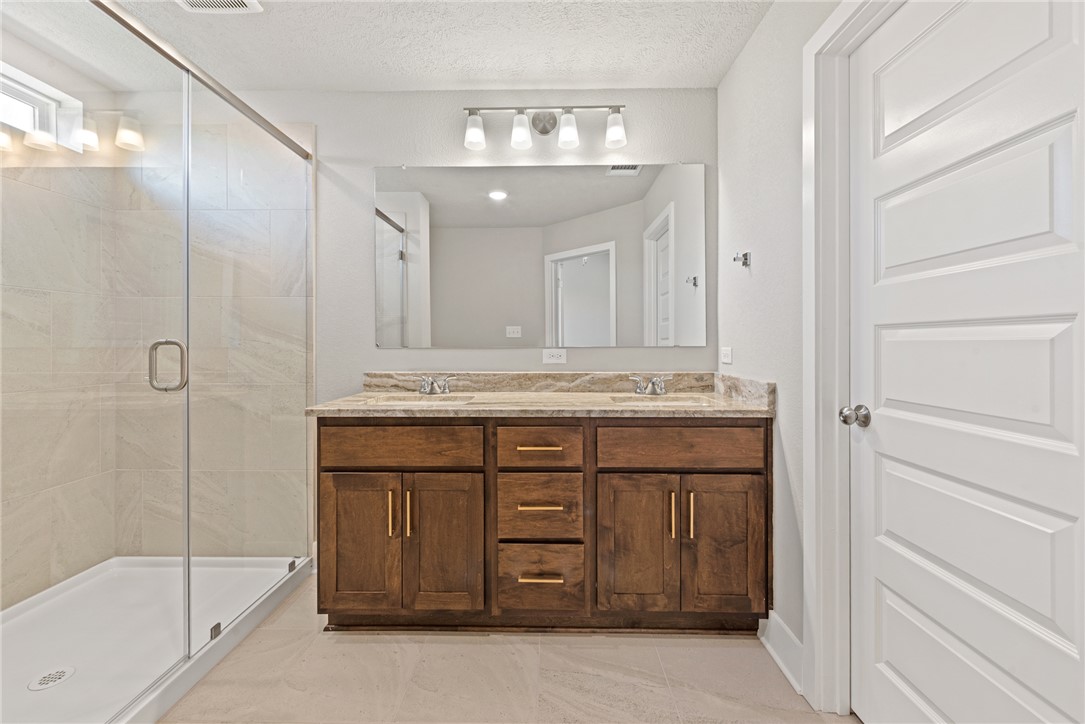 4245 Appalachian Trail Bryan, TX 77802 - Photo 26 of 30 a bathroom with a granite countertop sink a mirror and a shower