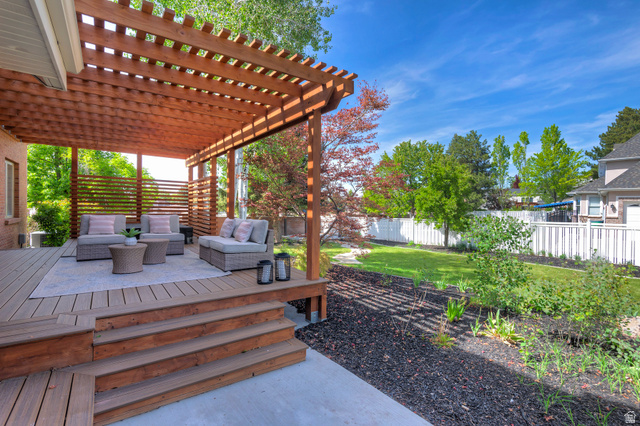 16 Gatehouse Lane Sandy, UT 84092 - Photo 19 of 73 Fully fenced backyard featuring outdoor seating, a pergola, and a private deck with garden beds.