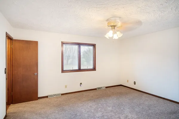 an empty room with a chandelier fan and windows