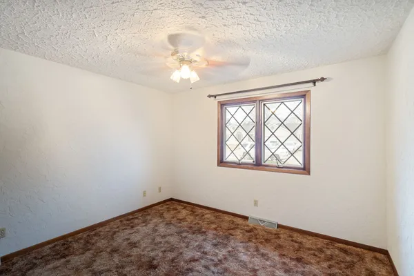 an empty room with a chandelier fan and windows
