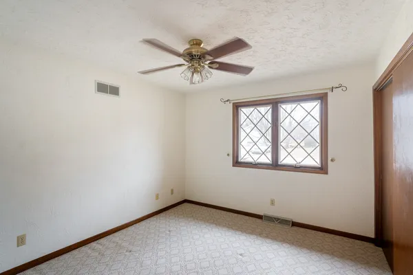 an empty room with windows and fan