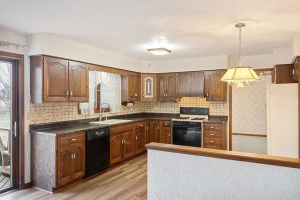 a kitchen with granite countertop a sink a counter space appliances and cabinets
