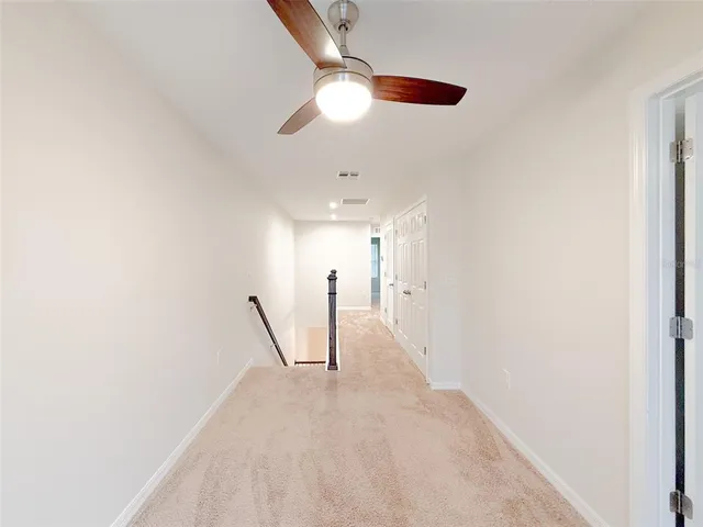 a view of a hallway with a chandelier fan