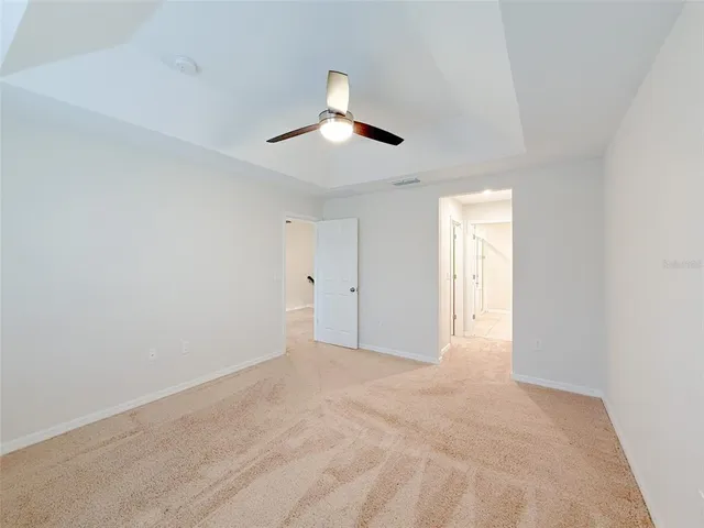 a view of an empty room and chandelier fan