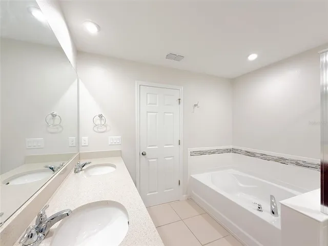 a en suite bathroom with a granite countertop tub sink and mirror