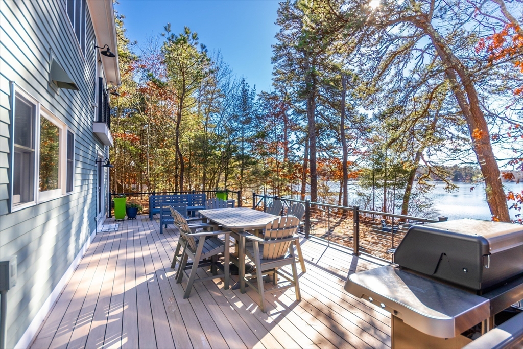 2 Blackmore Pond Circle Wareham, MA 02576 - Photo 40 of 42 a view of a patio with table and chairs and potted plants with wooden floor and fence