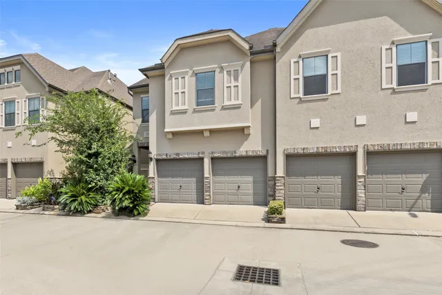 a front view of a house with garage and plants