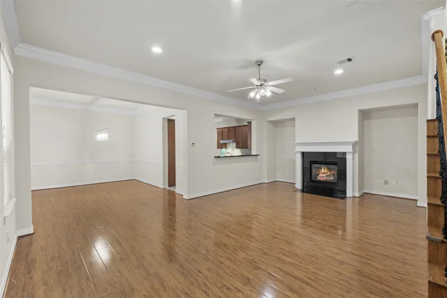 a view of an empty room with wooden floor and a fireplace