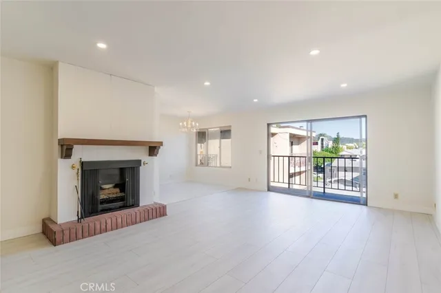an empty room with wooden floor fireplace and windows