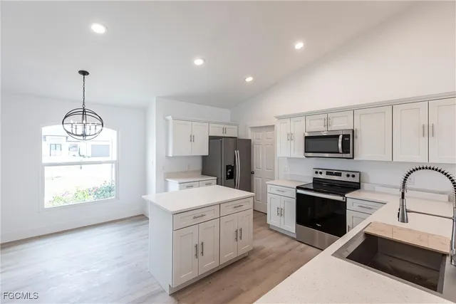 a kitchen with stainless steel appliances kitchen island granite countertop a sink dishwasher stove and refrigerator with wooden floor