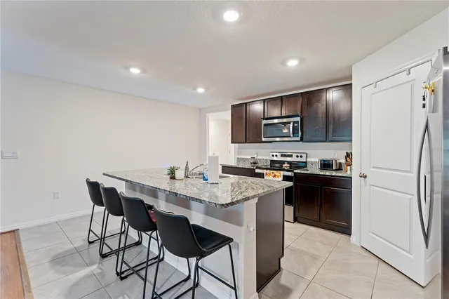 a kitchen with granite countertop a refrigerator stove microwave and cabinets