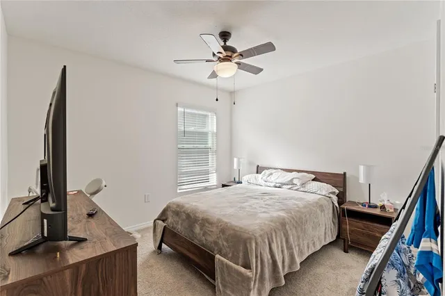 a bedroom with a bed and a flat tv screen on the dresser