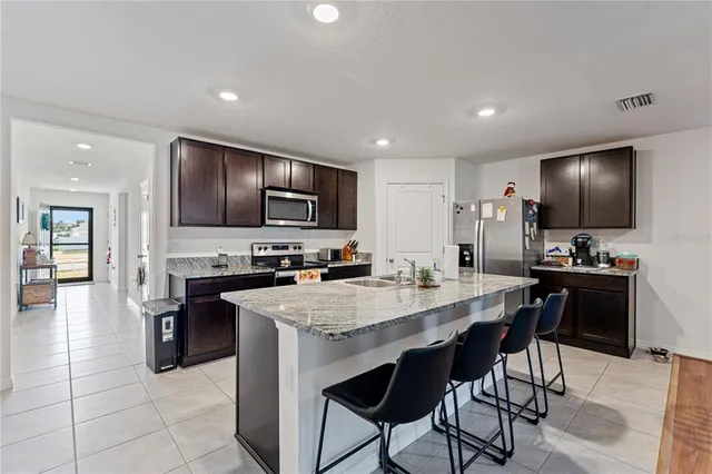 a kitchen with stainless steel appliances granite countertop a stove top oven a sink dishwasher a dining table and chairs with wooden floor