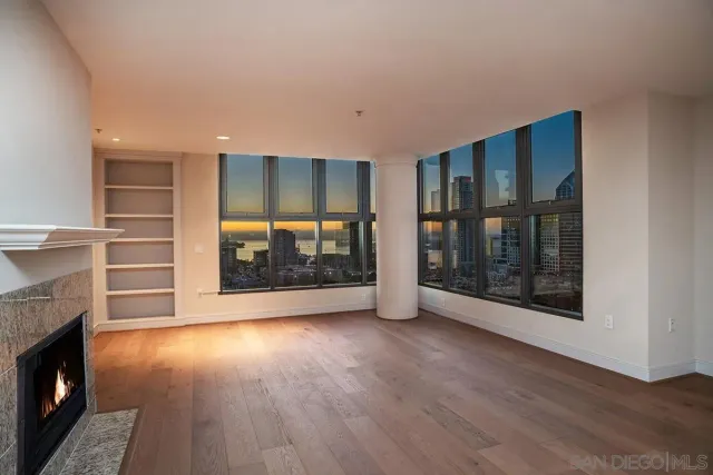 a view of an empty room with wooden floor fireplace and a window