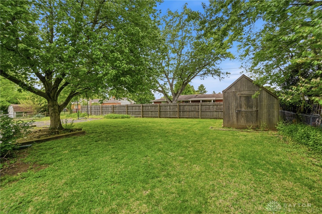 6119 Flemington Road Dayton, OH 45459 - Photo 65 of 76 This spacious backyard features a privacy fence and mature trees, offering an ideal setting for outdoor activities.