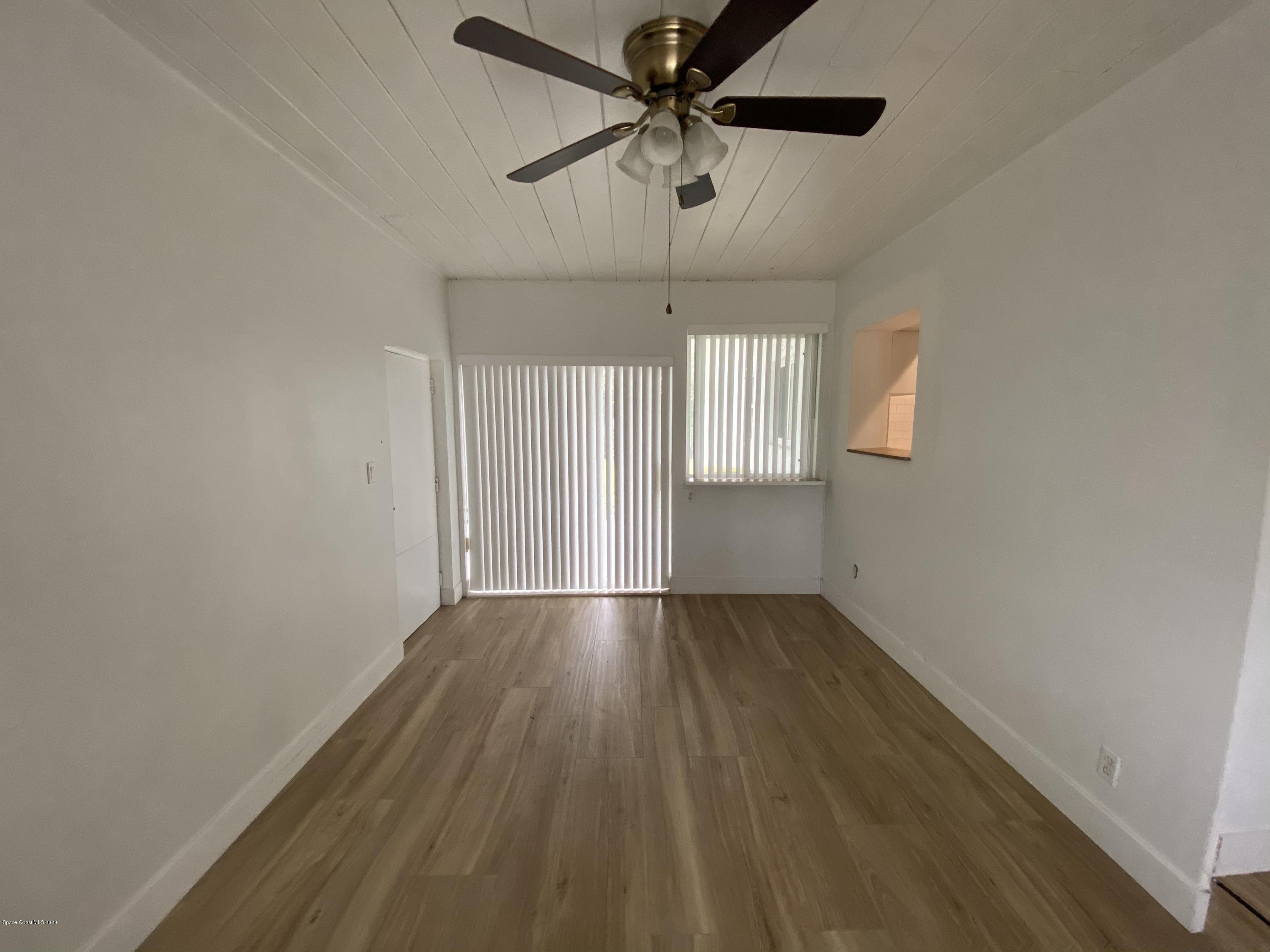 2309 Country Club Road Melbourne, FL 32901 - Photo 11 of 50 an empty room with wooden floor fan and windows