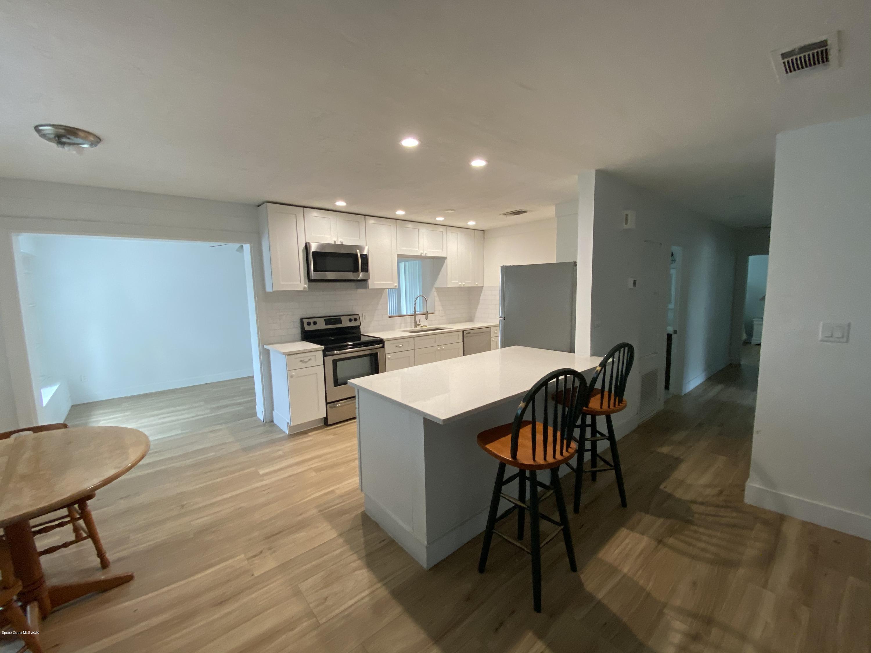 2309 Country Club Road Melbourne, FL 32901 - Photo 4 of 50 a kitchen with a table chairs refrigerator and microwave