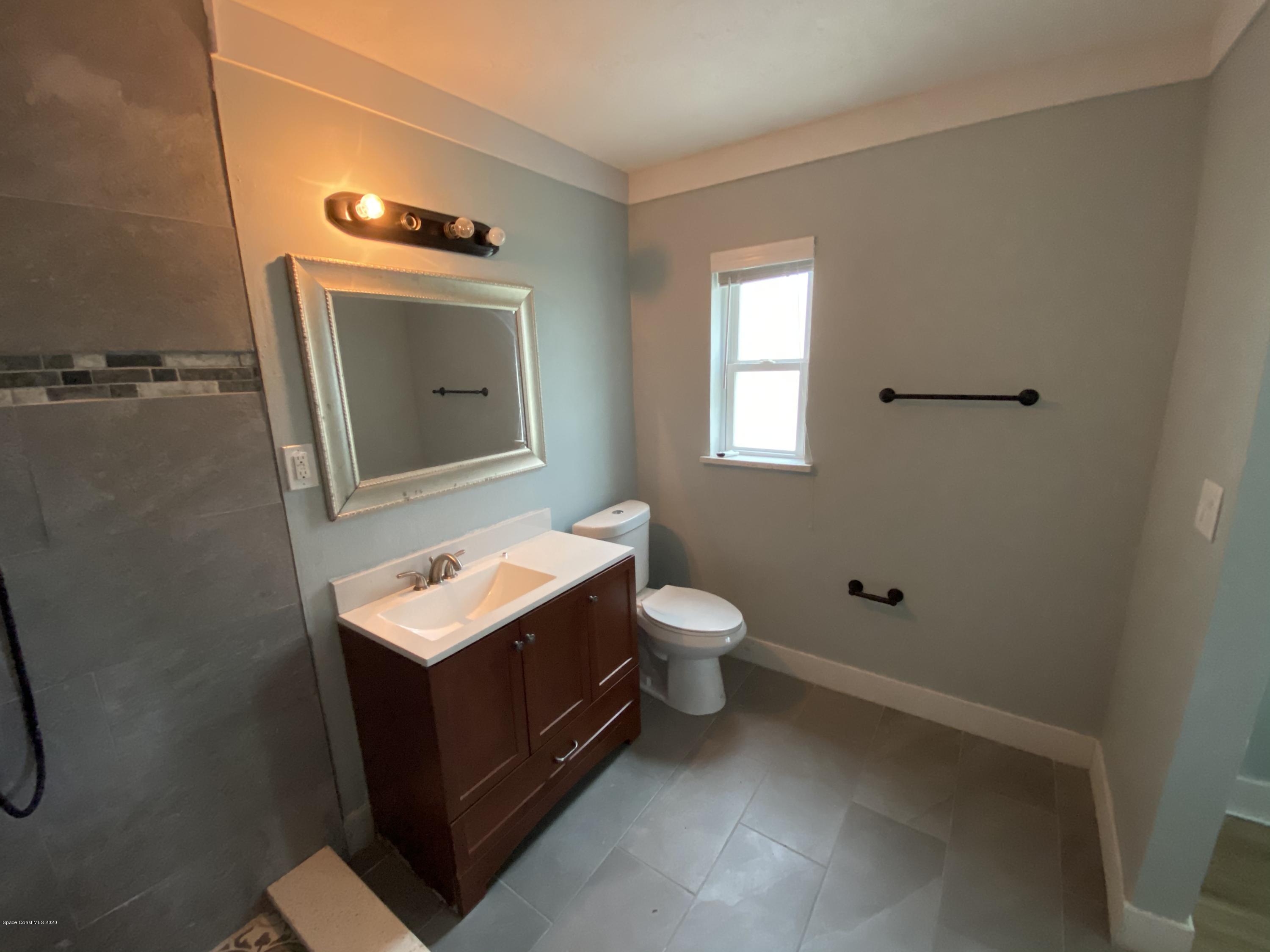 2309 Country Club Road Melbourne, FL 32901 - Photo 33 of 50 a bathroom with a toilet sink and mirror