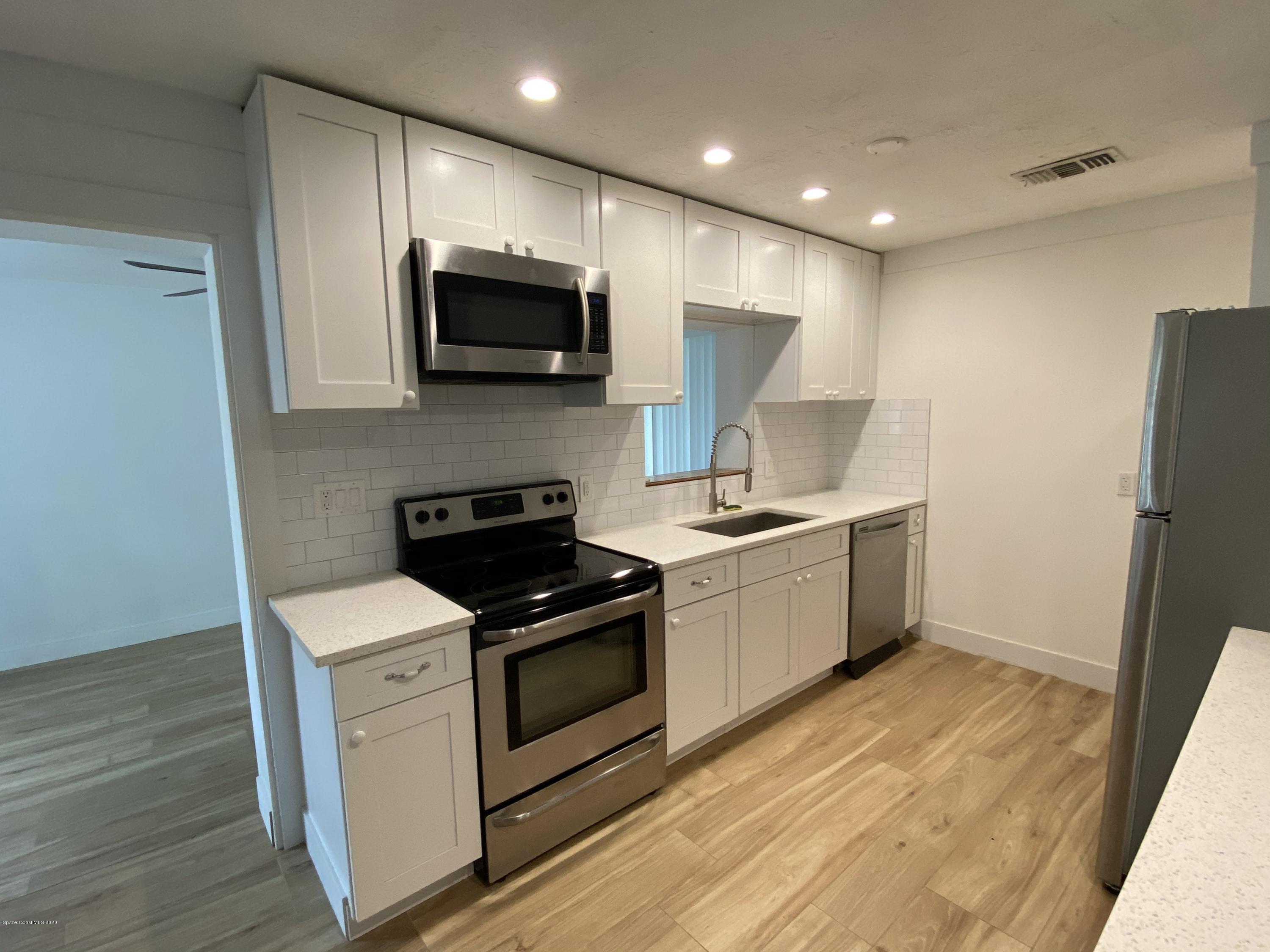 2309 Country Club Road Melbourne, FL 32901 - Photo 7 of 50 a kitchen with stainless steel appliances a white stove top oven a sink and a refrigerator