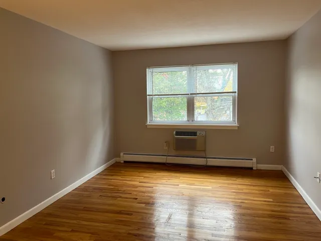 an empty room with wooden floor and a window