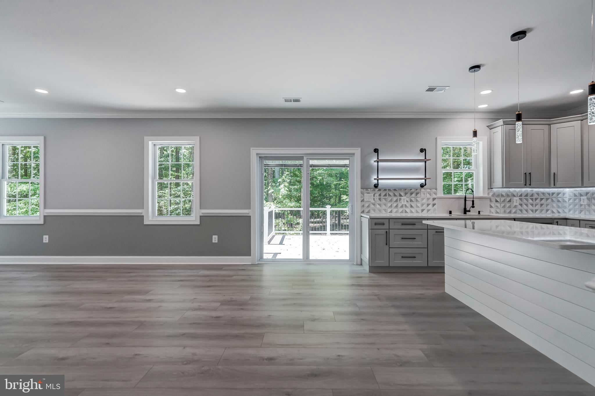 50 Retriever Court Bumpass, VA 23024 - Photo 24 of 77 a large kitchen with kitchen island granite countertop a stove a sink wooden floors and white cabinets