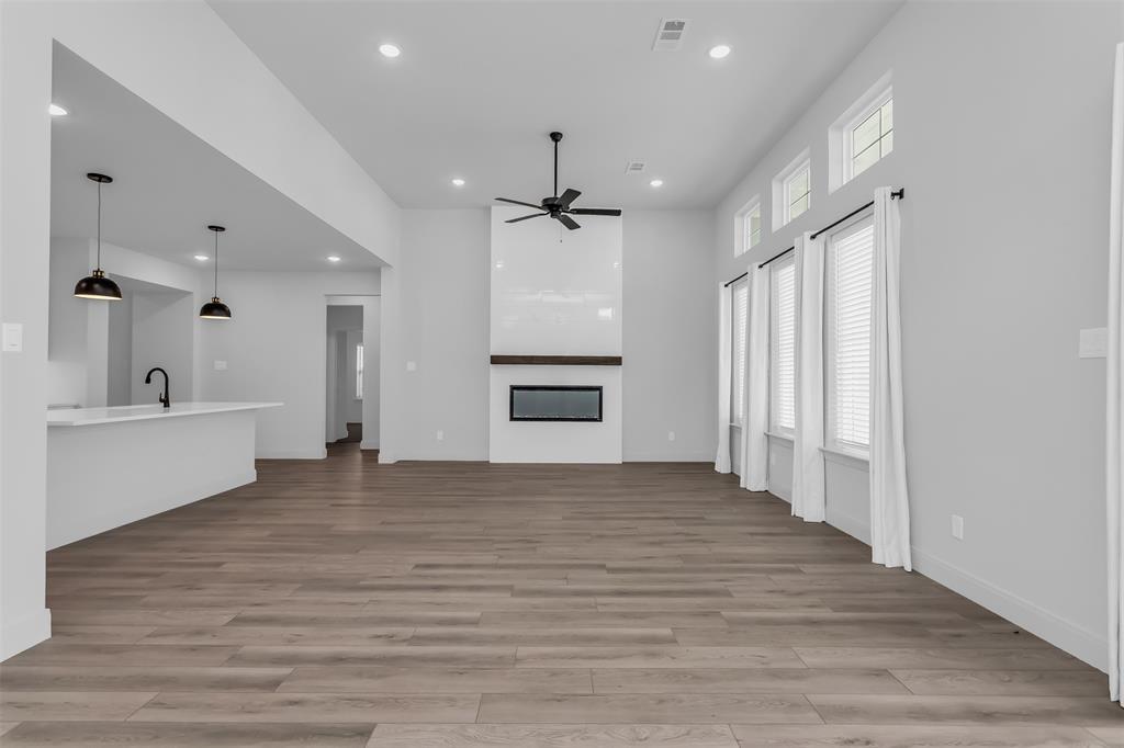 1031 Rylan Street Midlothian, TX 76065 - Photo 5 of 28 Spacious living area featuring wood-finish flooring, a modern fireplace with a wood mantle, and a ceiling fan