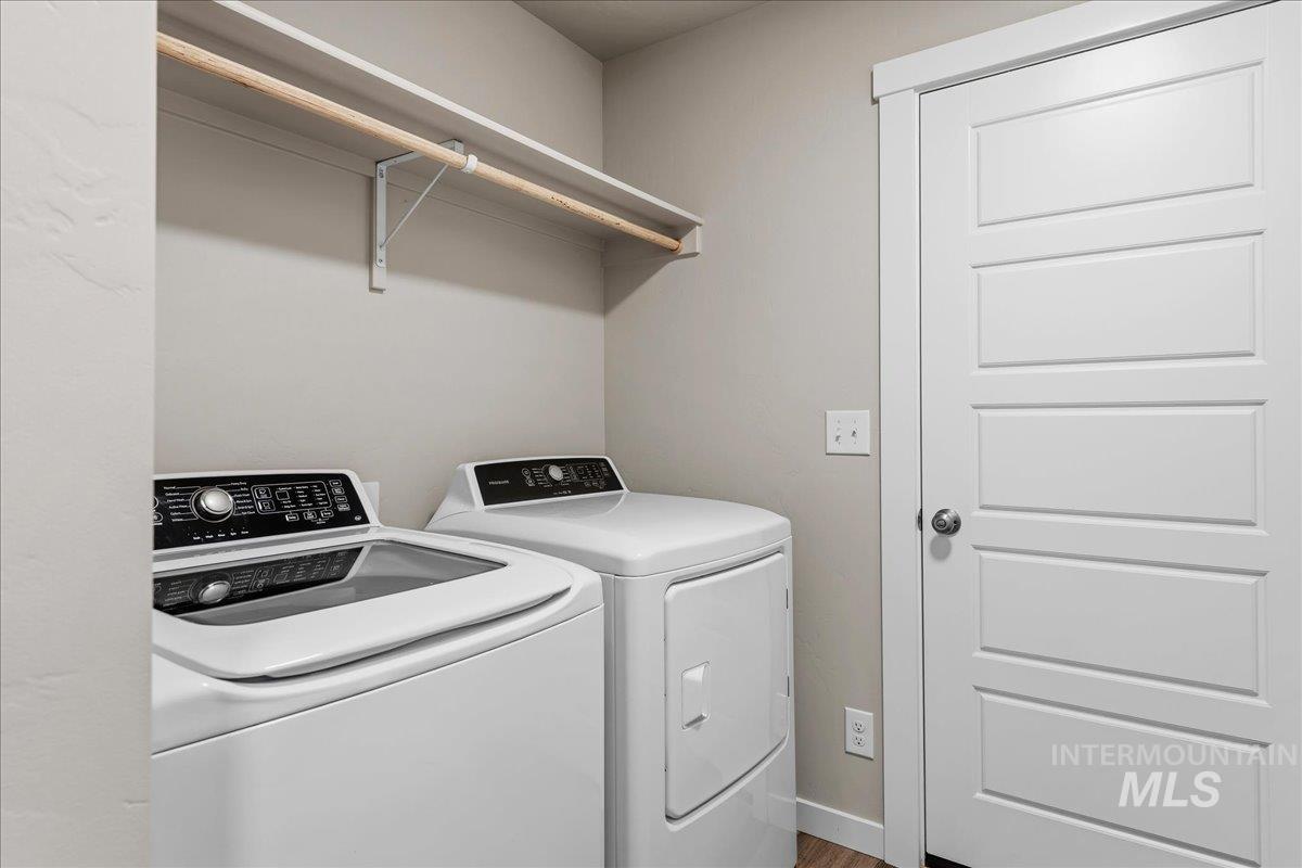3091 S Green Boise, ID 83709 - Photo 22 of 27 Dedicated laundry area featuring a white top-load washer, a white front-load dryer, and an upper shelf with a hanging rod