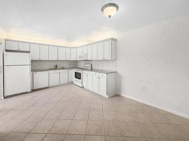 a kitchen with white cabinets and white appliances