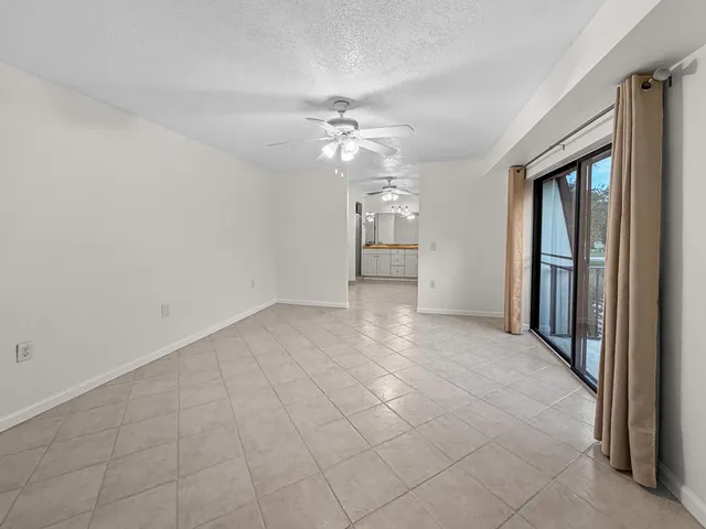 an empty room with chandelier fan and windows