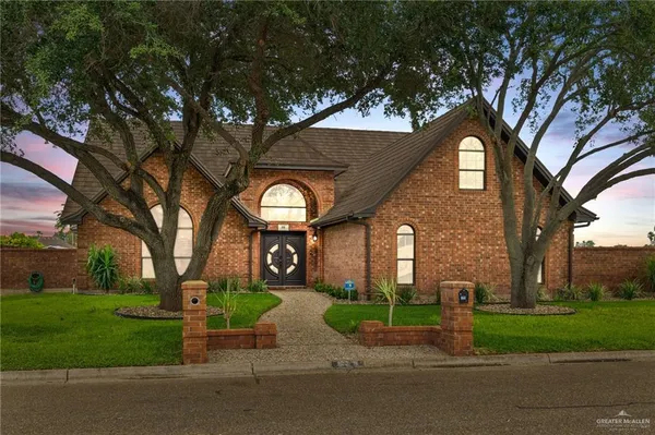 a view of a house with a yard and large trees
