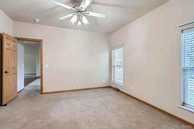 an empty room with chandelier fan and windows