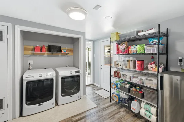 a utility room with stainless steel appliances and a wooden floor