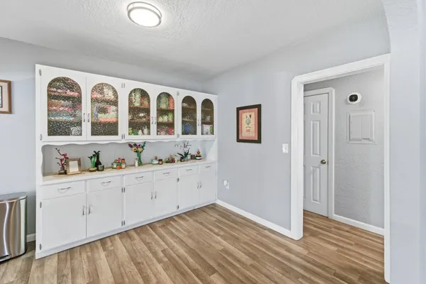 a view of an empty room with wooden floor and cabinets
