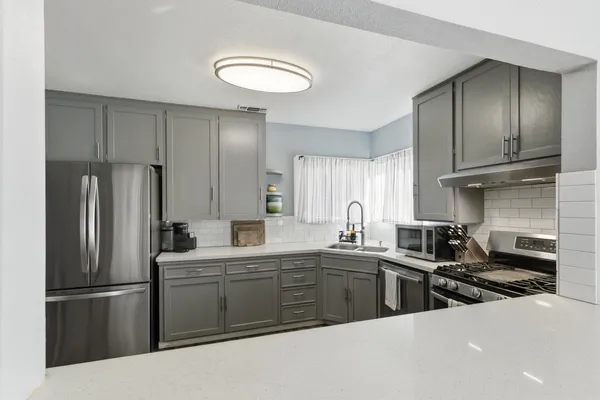 a kitchen with stainless steel appliances a sink a stove a refrigerator cabinets and a window