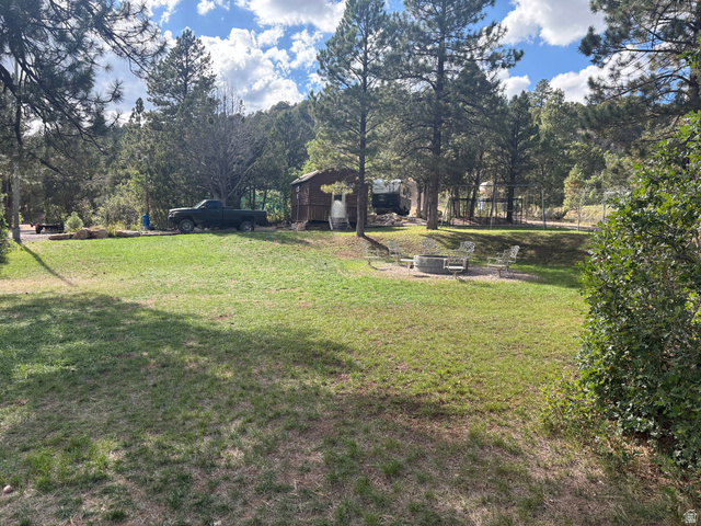 700 West Gravel Road North Kanab, UT 84741 - Photo 60 of 63 Grassed yard with mature trees, a built-in fire pit, and a wooded backdrop