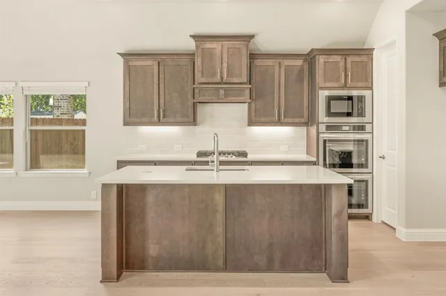 a kitchen with stainless steel appliances granite countertop a sink and a refrigerator