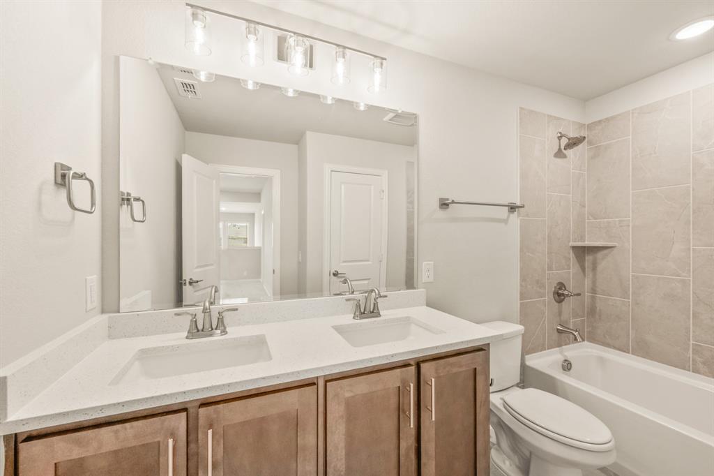 1098 Foxtail Drive Justin, TX 76247 - Photo 36 of 40 a bathroom with a granite countertop sink a toilet a shower and a mirror