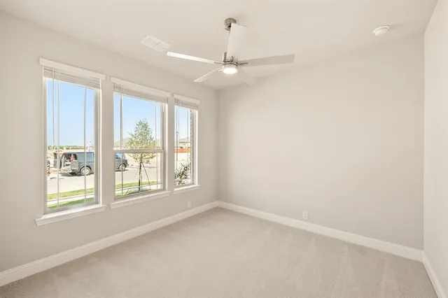 en empty room with windows and ceiling fan
