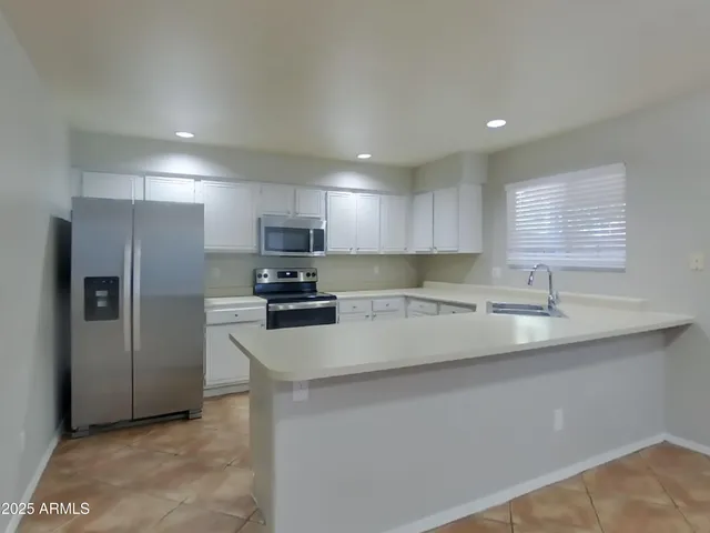 a kitchen with white cabinets appliances a sink and a window