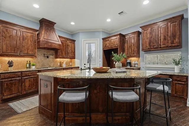 a kitchen with granite countertop wooden cabinets and chairs