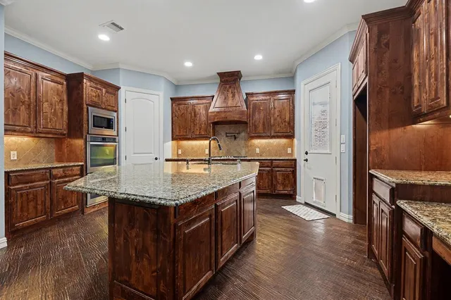 a kitchen with stainless steel appliances granite countertop a kitchen island a stove a sink and a refrigerator
