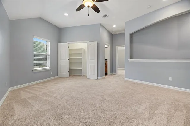 an empty room with chandelier fan and windows