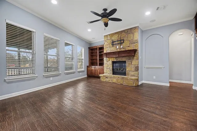 a view of an empty room with wooden floor fireplace and a window