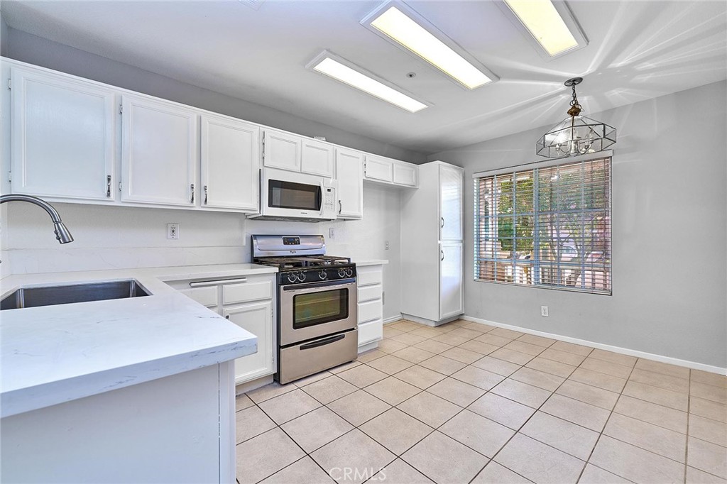 5280 Melbourne Place Riverside, CA 92508 - Photo 22 of 59 a kitchen with granite countertop a stove a sink and a microwave