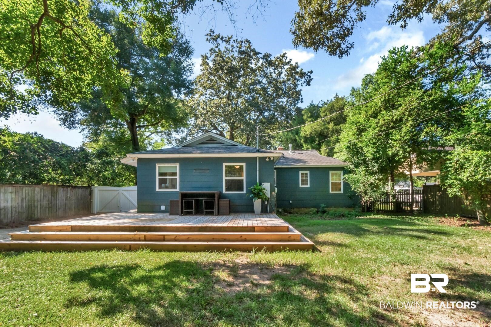 18 Princess Anne Road Mobile, AL 36608 - Photo 34 of 41 Back of house with a wooden deck, view of scattered trees, and a gate