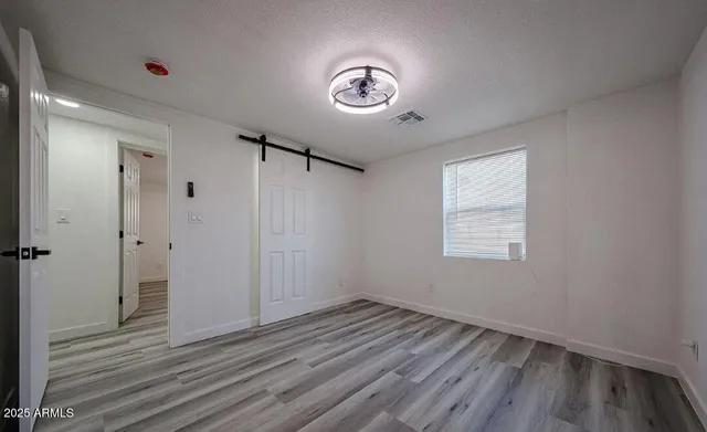 a view of an empty room with a window and wooden floor