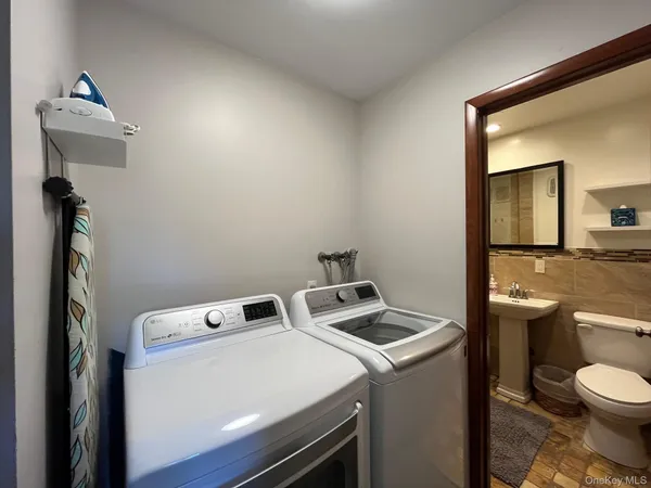 a view of washer and dryer with bathroom in the background