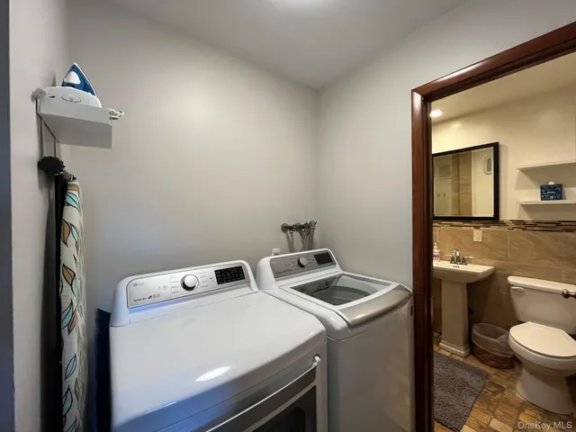 a view of washer and dryer with bathroom in the background
