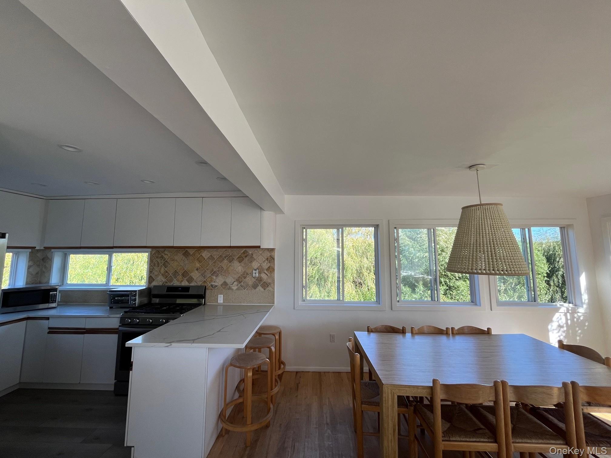 150 Clipper Way Ocean Beach, NY 11770 - Photo 7 of 27 a kitchen with a table chairs a sink dishwasher window and cabinets