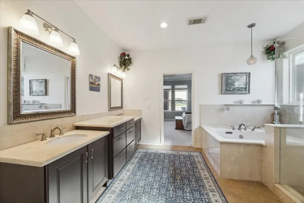a spacious bathroom with a tub sink and mirror